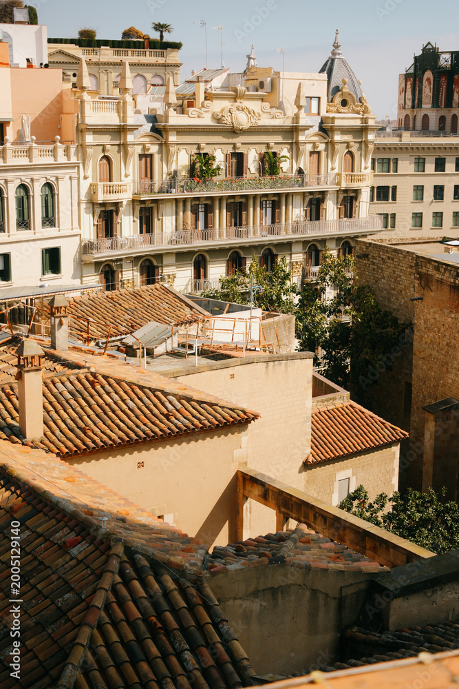 Fototapeta premium Beautiful architectural view of historic buildings with ornate balconies and terracotta rooftops in Barcelona, Spain. Sunny day in the Eixample district with classic Mediterranean facades