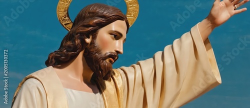 Majestic statue of Jesus Christ with halo, raising his arm against a clear blue sky, representing divine blessing and salvation.