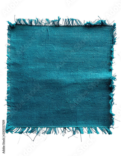 A close-up shot showcases a distressed, teal-colored fabric square against a stark black background, highlighting its frayed edges and textured surface.
