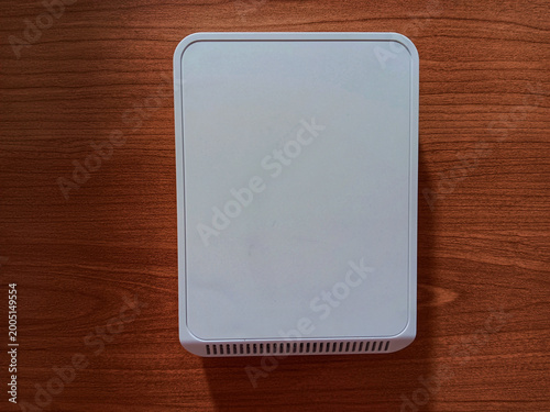 A white wall mounted sensor for monitoring indoor air quality and temperature in building management system isolated on wooden background.