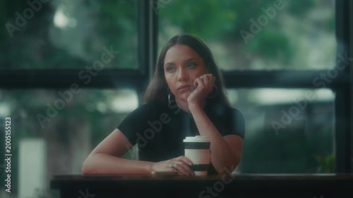 Serene Female Writer Lost In Her Thoughts. Calm Woman Seated At Cafe Window Reflecting Peacefully
