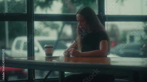 Serene Female Writer Lost In Her Thoughts. Calm Woman Seated At Cafe Window Reflecting Peacefully