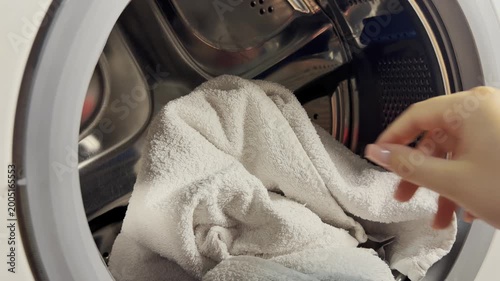 Stacking dirty white towels in the washing machine. A woman organizes clean white laundry towels into neat stacks to keep things fresh in the bathroom and laundry care.