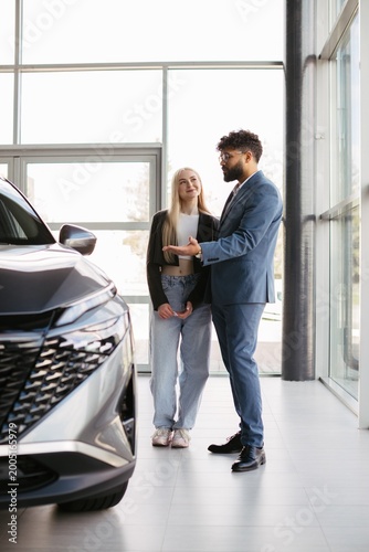 Salesman presenting new car to young customer
