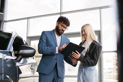 Canvas Print Salesman assisting female client with new car purchase paperwork