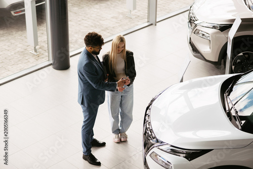 Obraz na plátně Salesman explaining car features to female customer in dealership