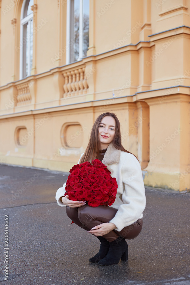Fototapeta premium Beautiful Young Woman Holding Bouquet of Red Roses in Romantic Elegant Portrait
