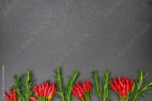 Foto Red chilies and rosemary arranged on a dark background in a simple layout during