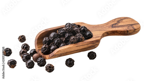 Bild auf Leinwand Wooden scoop overflowing with black peppercorns and scattered around