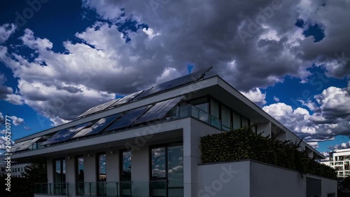 Apartment building with rooftop solar panels and moving clouds, timelapse