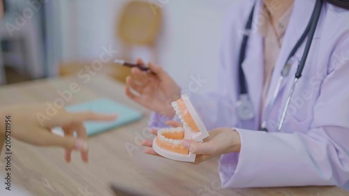 The dentist is talking to the patient and showing them a model of the teeth. (Concept of dental care)