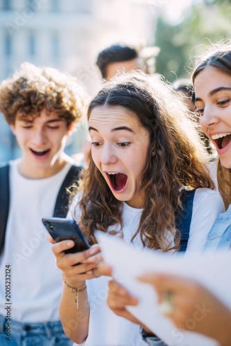 Happy students reacting excitedly while checking exam results on smartphone, close-up emotional moment, campus background softly blurred, natural sunlight visual for editorial concept
