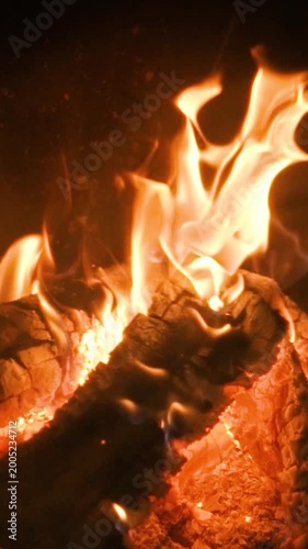 A home fireplace with a bright orange flame and logs burns and warms the room. Comfort and warmth in the cold winter atmosphere.