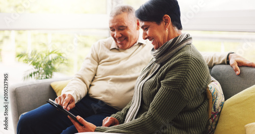 Canvas Print Happy, tablet and senior couple on sofa in home with watching film show or series together
