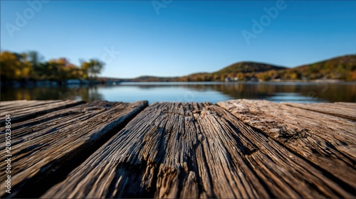Close-up view of weathered wooden planks leading to a calm lake under a clear sky