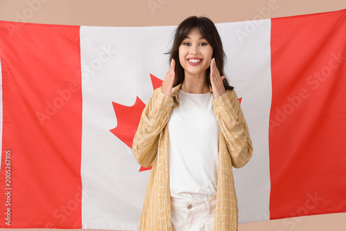 Young woman against flag of Canada on beige background