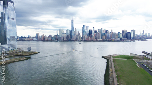 Bild auf Leinwand Riverfront skyline sweeps capture Hudson River edge near Liberty State Park facing Lower Manhattan tower cluster, One World Trade Center rising