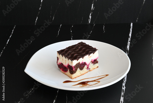 Donauwelle Kuchen auf weißem Teller vor dem dunklem Hintergrund