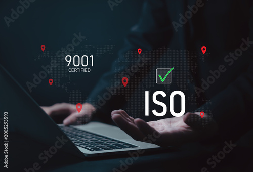 Businessman touching virtual checkmark icon for ISO 9001 certification on digital world map background, symbolizing quality management, compliance, global standards, and corporate assurance in modern.