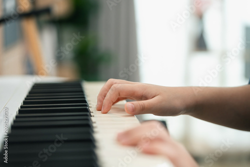 Close-Up of a Child's Hand Playing Piano Keys in a Bright and Cozy Indoor Setting with Soft Natural Lighting and Relaxing Atmosphere