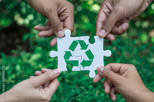 Hands holding puzzle pieces forming a green recycling symbol sustainability