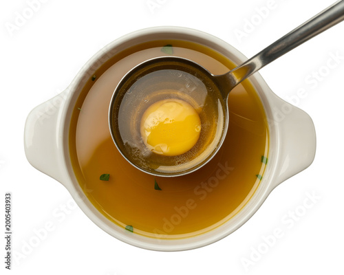 Top-down view of white ceramic bowl with golden broth and black chopsticks
