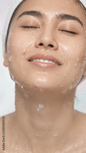 Young woman is washing her face with water