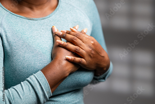 Photos African woman experiencing chest pain or discomfort, holding hands over her hear