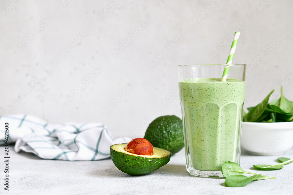 Fototapeta premium Detox avocado spinach smoothie in a tall glass. Top view with copy space.