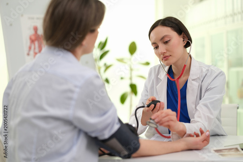 Bild auf Leinwand Physician measuring patient blood pressure with sphygmomanometer cuff on arm, fo