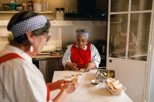 Diverse senior female chefs working together to bake delicious handmade tarts in a professional bakery setting