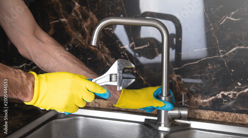 Man repairs a kitchen faucet.