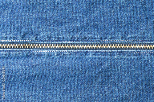 Denim zipper repair. Closeup of denim with zipper. Tailor repairing denim pocket under studio lighting. Indigo denim fabric with brass hardware and textured weave details