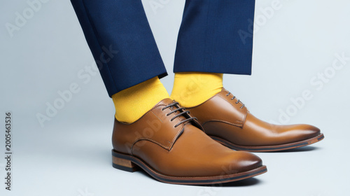 The image shows brown leather dress shoes paired with bright yellow socks and dark navy trousers