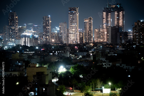 Fotografie Modern highrise multi storey skyscrapers at night with lights shining through wi