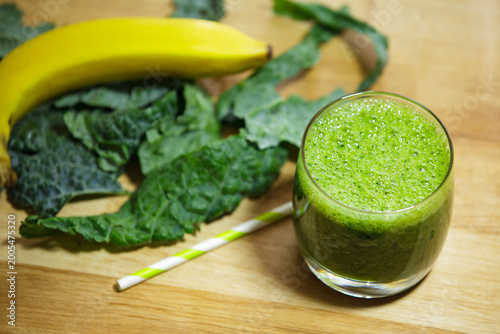 Glass of Nutritious Green Smoothie with Kale and Banana on Wooden Table