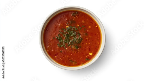 Overhead view of a bowl of vibrant red soup, garnished with fresh herbs