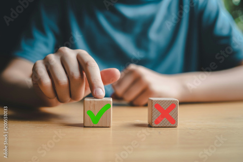Person hand pressing wooden block with green check mark symbol for approval.