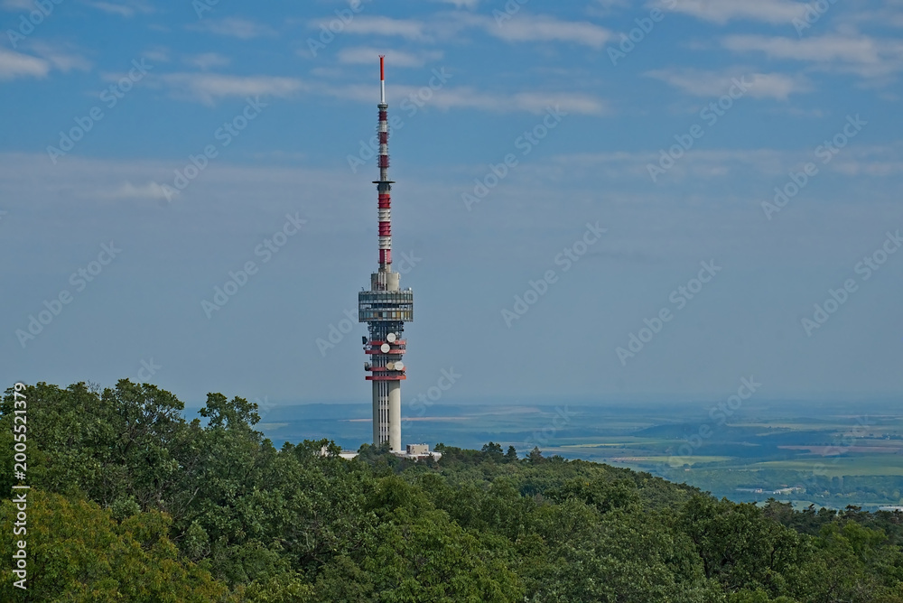 Obraz premium Red and white telecommunications antenna surrounded by forest in the Mecsek ills around Pecs, Hungary 