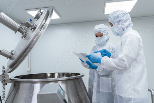 Obraz na plátne Two technicians wearing white protective suits and face masks