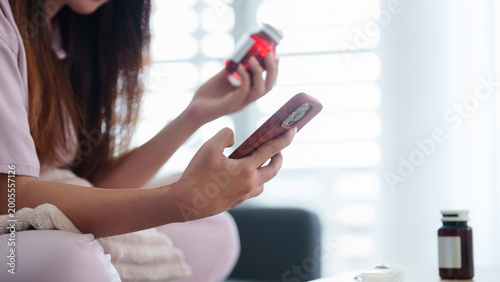 Bild auf Leinwand Asian women using smartphone reading medicine bottle label checking prescription