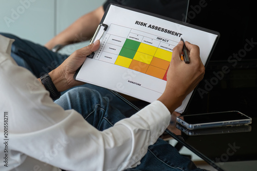Fotografie Close up of Business Team in Risk Assessment Meeting with Clipboard Matrix