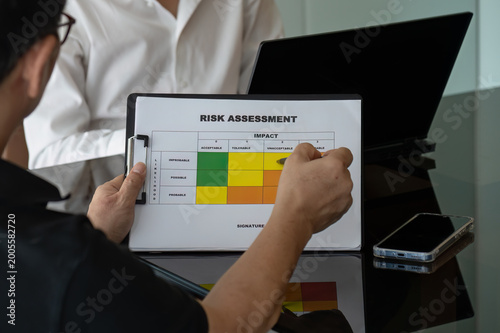 Close up of Business Team in Risk Assessment Meeting with Clipboard Matrix