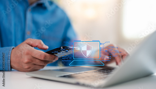 Hand of a man using mobile phone and laptop, secure access to user personal information, secure Internet access, information security encryption. Cybersecurity internet network data privacy concepts.