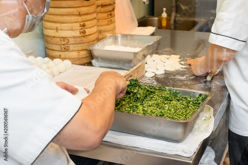 Photos In a semi-open kitchen, chefs carefully prepare xiaolongbao by flattening dough into thin wrappers and filling them with minced pork and chives