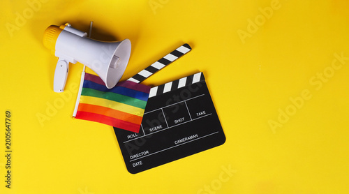 Clapper board and rainbow pride flag and megaphone on yellow background.