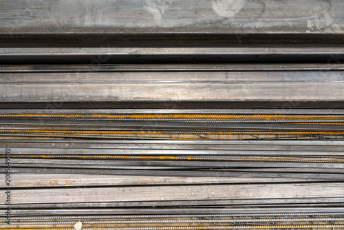 Stack of rectangular steel pipes and metal profiles lying on paving stones outdoors. Industrial material photography. Construction and metalworking industry concept. Design for banner, poster.