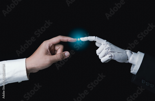 Human finger touching robotic finger with glowing light for AI connection concept