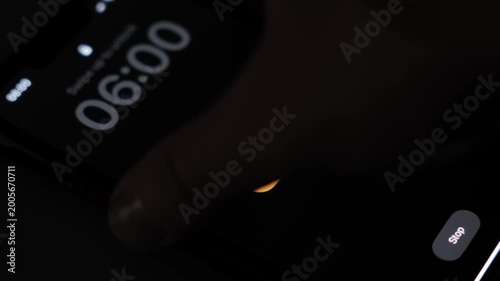 A smartphone screen lights up in a dark room as a 6 AM alarm turns on with the run label showing an early morning fitness routine and wake up moment. High quality 4k footage
