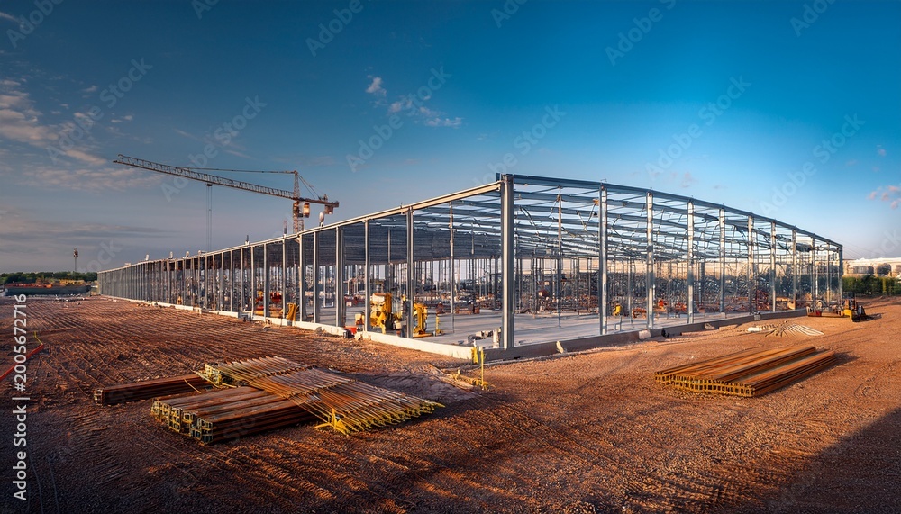 Fototapeta premium construction of a steel frame warehouse in an open area near a city during the day